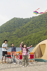 湖边露营烧烤放风筝的3人图片