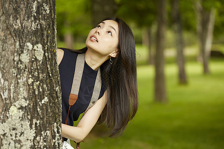 长发女孩向大树上方看去图片