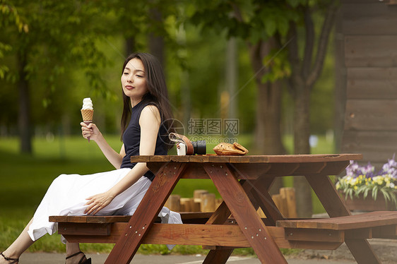 拿着冰淇淋坐在木椅子上的成熟女性在思考图片