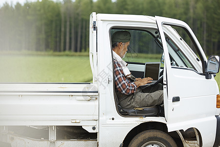 农民在农用车上用笔记本电脑背景图片