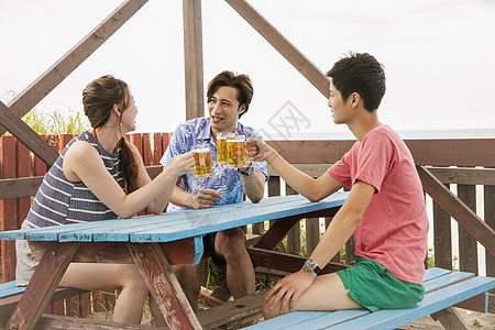 海边小屋喝啤酒聊天的青年图片