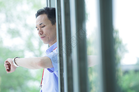 站在楼门口抬手看时间的中年男性图片