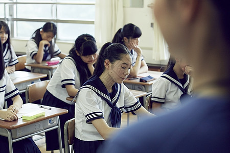 过肩拍摄认真答卷的学生图片