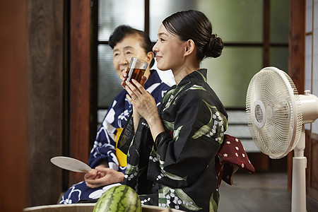 夏日日式房屋中吃西瓜喝饮料的2人图片
