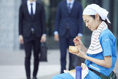 在办公楼下吃午餐的女清洁员图片