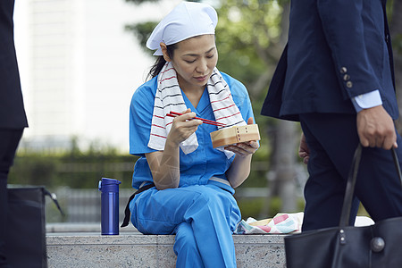 在办公楼下吃午餐的女清洁员图片