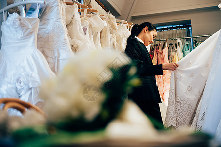 婚纱店内整理婚纱的婚礼策划师形象图片