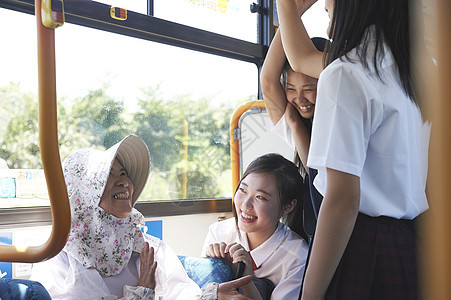  一群学生和坐公交车的奶奶交谈图片