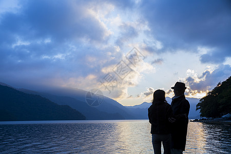 家人剪影旅游的中年夫妇在湖边看风景背景