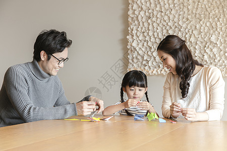 一家三口坐在桌前玩亲子游戏图片
