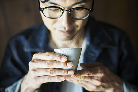 手捧茶杯的年轻男性图片