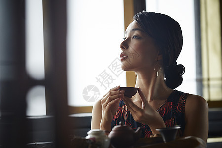 女人在茶馆窗台边品茶看窗外图片