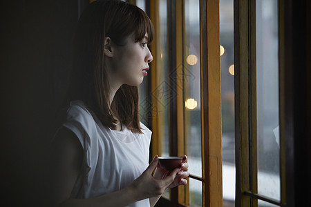 女人在茶馆窗台边品茶看窗外图片