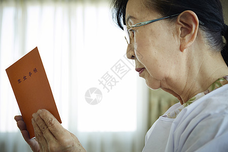 独居老妇人戴着眼镜看年金手账本图片