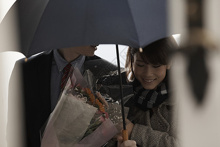 女孩牵着打着伞拿着花的男友上楼高清图片
