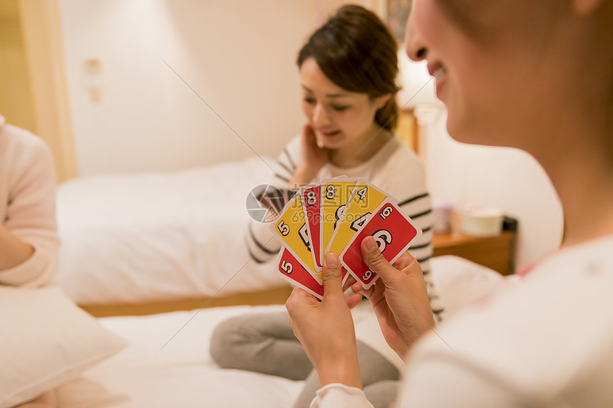 朋友聚会穿着睡衣的女人在卧室玩纸牌游戏图片
