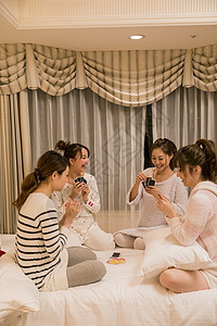 朋友聚会穿着睡衣的女人在卧室玩纸牌游戏图片