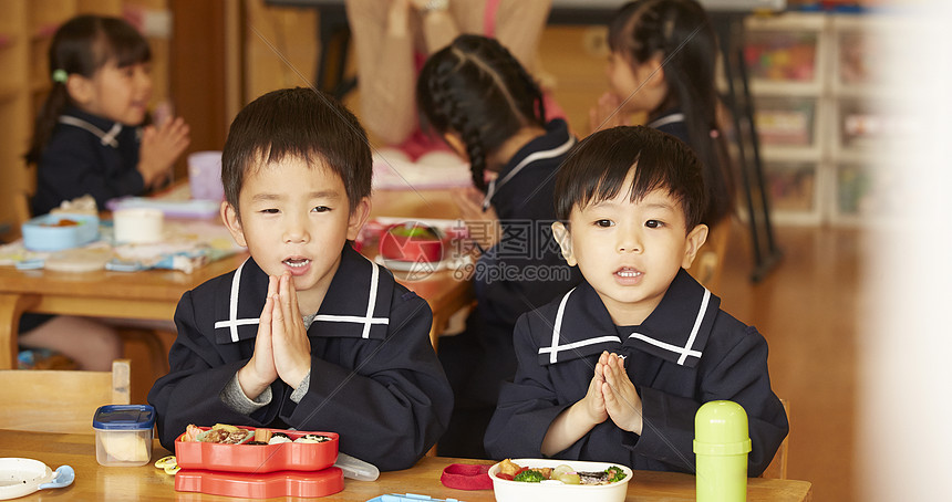 午饭时间在餐桌前双手合十的小男孩图片