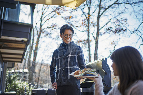 女生将食材端给男生准备烧烤图片