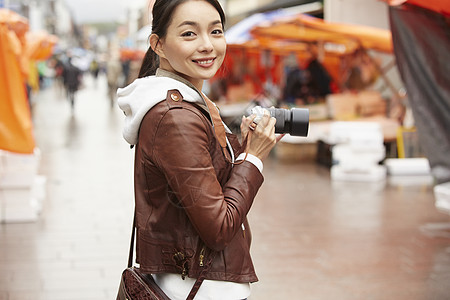 美女手拿相机逛集市图片