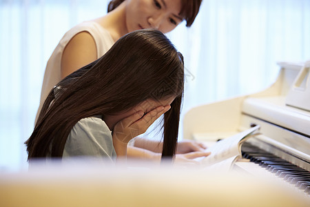 老师看着钢琴前哭泣的女孩图片