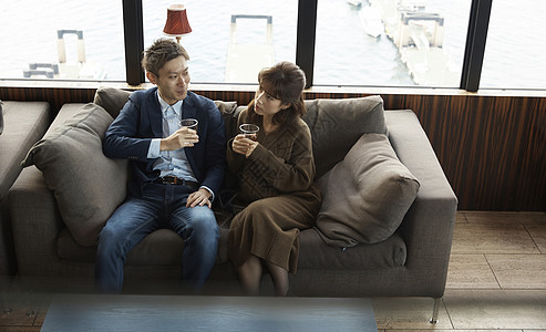坐在休息室沙发上休息喝酒的夫妇背景图片