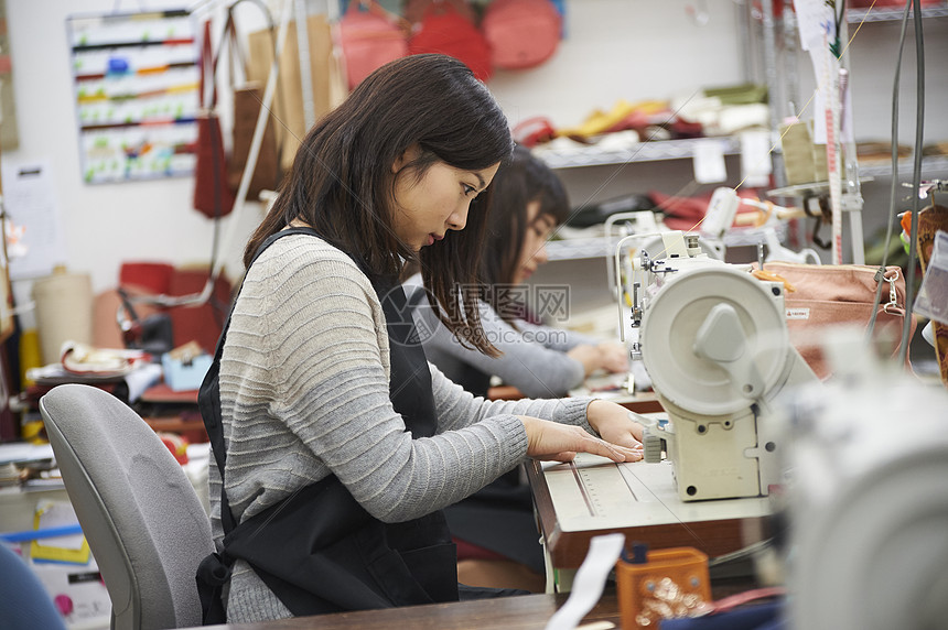 漂亮蓝领工人坐着制作帆布产品的女