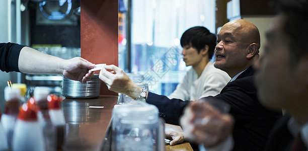 递给服务员食品券坐着等待食物上桌的男人图片