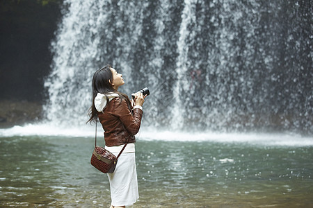 站在瀑布前的女性摄影师观光客高清图片素材