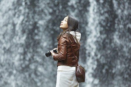 站在瀑布下拿着相机的女青年小国町高清图片素材