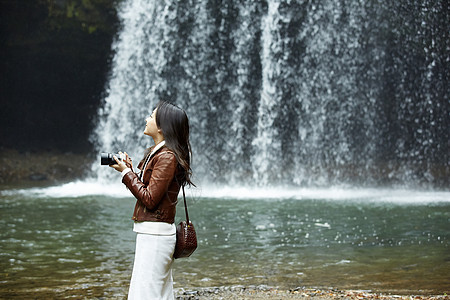 清澈的小溪旁拿着相机的女青年日本人高清图片素材
