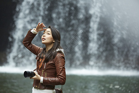 清澈的小溪旁拿着相机的女青年游览高清图片素材