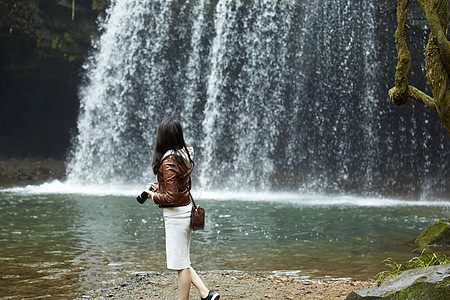 小溪边看着瀑布的年轻女性图片
