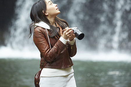 瀑布下拿着相机的女青年图片