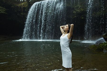 站在小溪边享受瀑布的女人在舒展身体背景图片