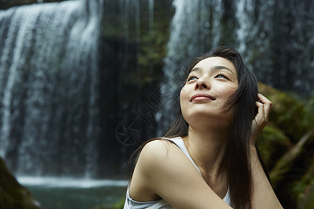 站在小溪边享受瀑布的女人抬头看图片