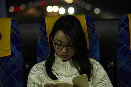 夜晚巴士上阅读的女青年图片