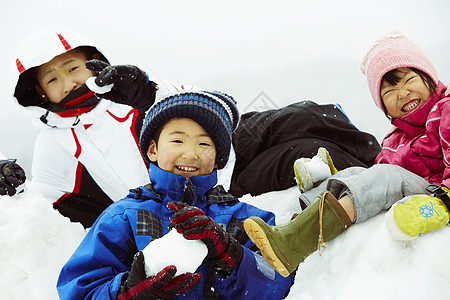 坐在雪地上捏着冰球的孩子们高清图片