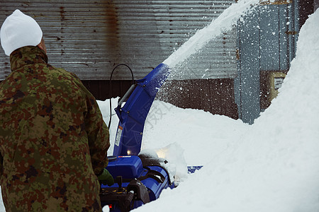 户外积雪使用除雪机的男性背影高清图片