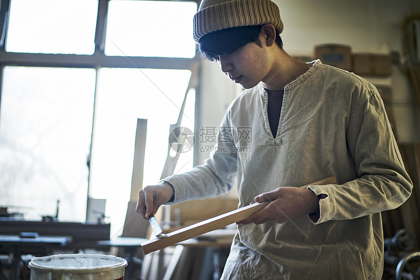 年轻工匠人在木块上刷胶图片