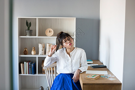 戴眼镜的女孩在书房拿着笔思考图片