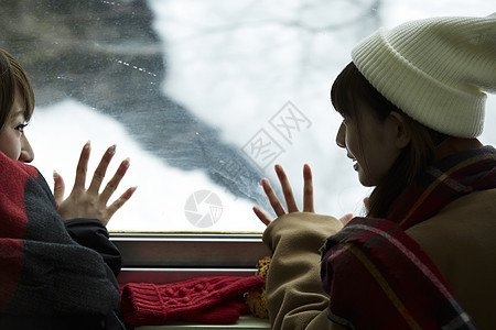冬季两位女学生一起看向窗外的雪图片