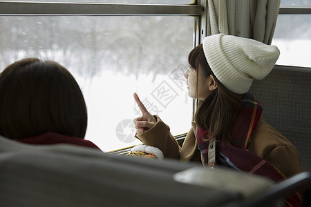 冬季两位女学生一起看向窗外的雪图片