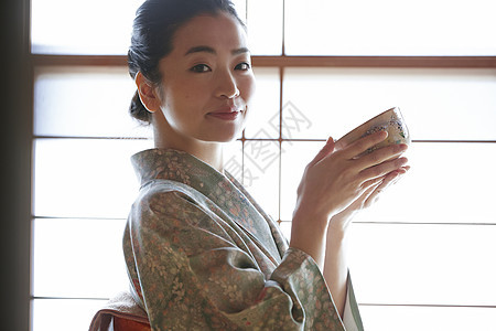 穿着日式服装捧着茶碗的年轻女性图片