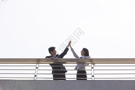 商务都市男女站在天桥上击掌图片