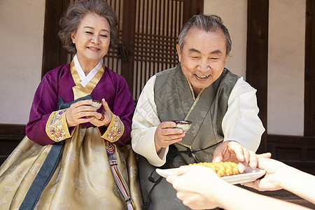 穿着传统服装喝茶拿着糕点的夫妇图片