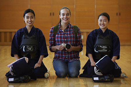 拿着相机的留学少女坐在剑道少女中间图片