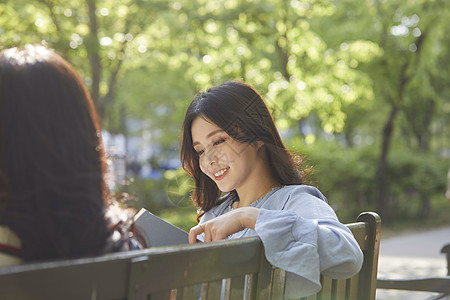 坐在长凳上聊天的年轻女子图片