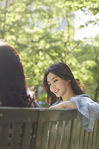 坐在长凳上聊天的年轻女子图片