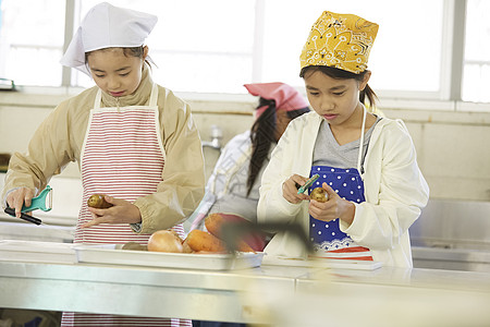 厨房里穿着围裙戴着头巾料理食材的女孩们图片